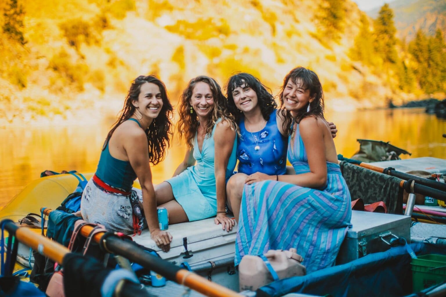 Four women pose and smile on a raft on the Main Salmon River in Idaho.