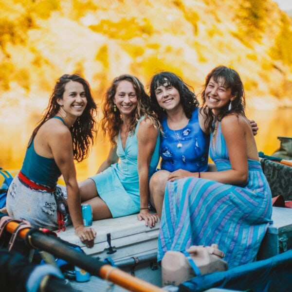 Four women pose and smile on a raft on the Main Salmon River in Idaho.