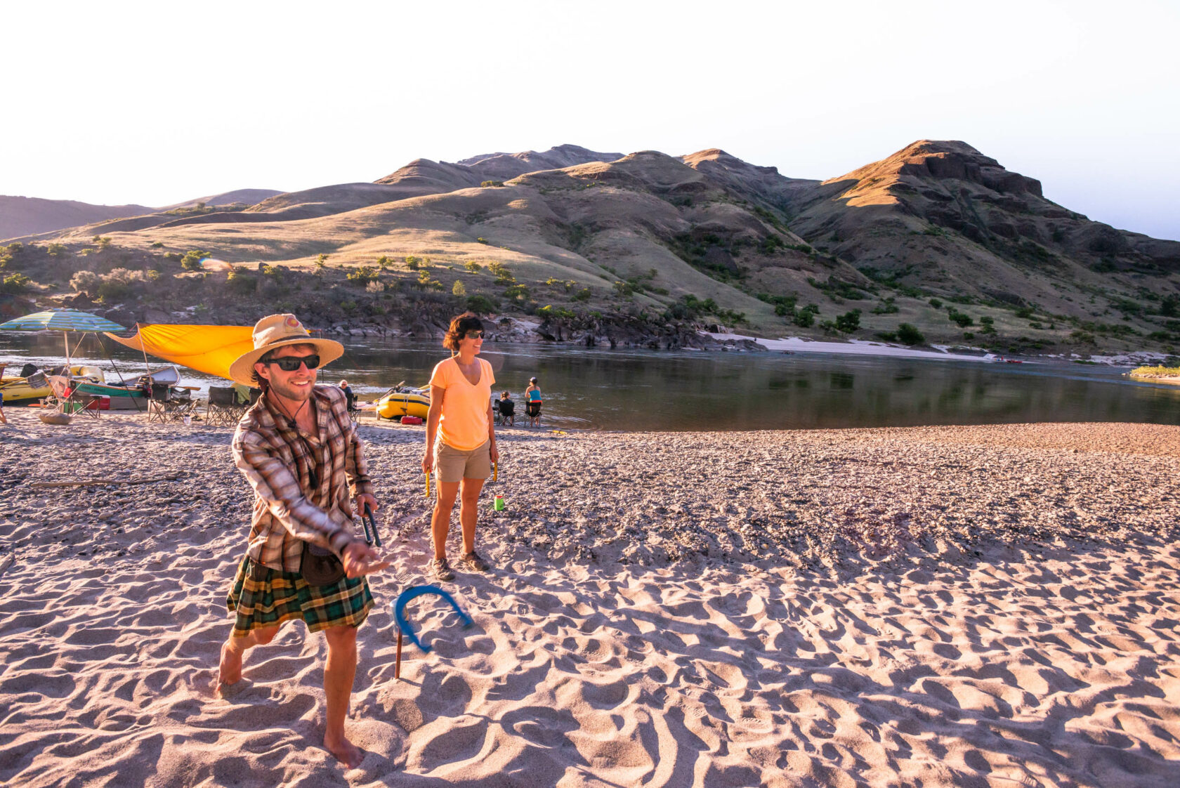 Adults playing horseshoes on the river bank.