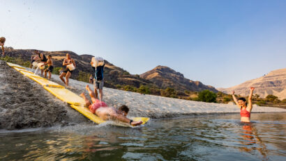 A man sliding down a a makeshift slip n' slide into a river