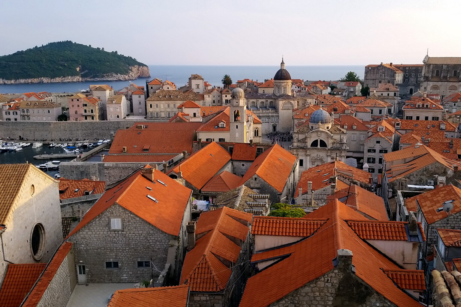 View from high above of historical architecture featuring orange roofs in a sea side town in Croatia.