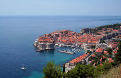 View from high above of a historical village in Croatia surrounded by a vibrant blue ocean.