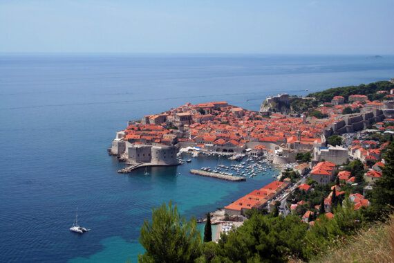 View from high above of a historical village in Croatia surrounded by a vibrant blue ocean.