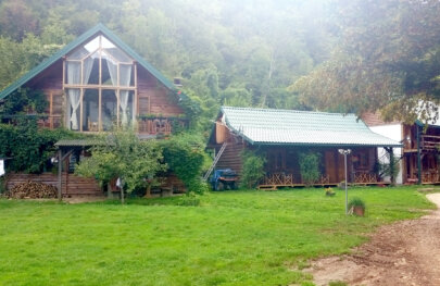 Charming log cabins sit up against a rising treeline at the base of a mountain in Croatia.