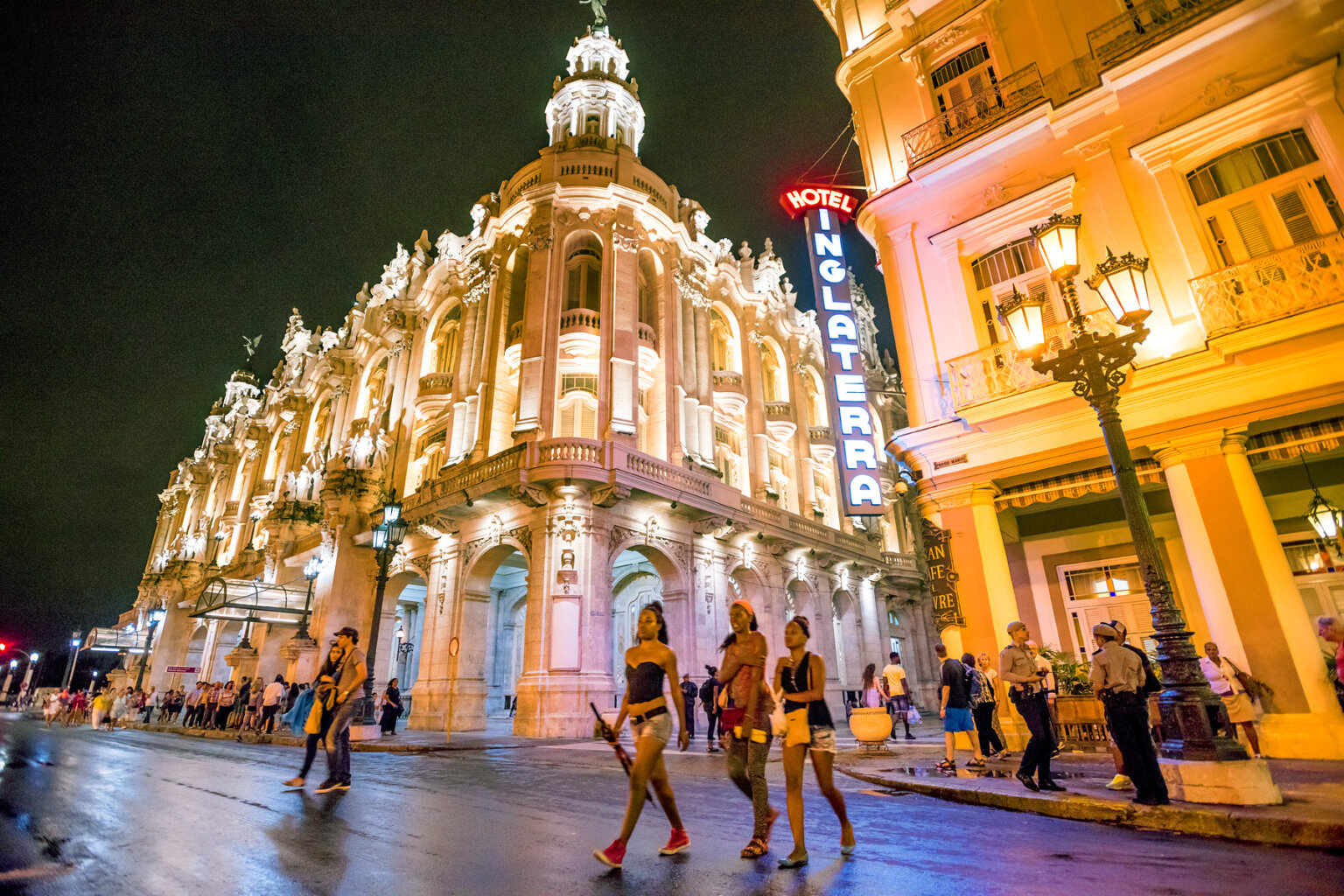 Night shot of a bustling city crowd in front of the Hotel Inglaterra in Cuba.