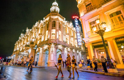 Night shot of a bustling city crowd in front of the Hotel Inglaterra in Cuba.