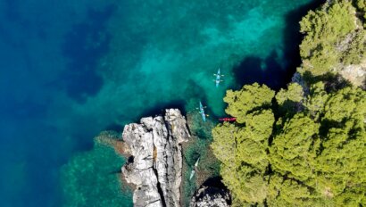 A group of kayakers paddling a craggy shoreline along the Dalmation Coast in Croatia, one of the top sea kayaking destinations in the world.