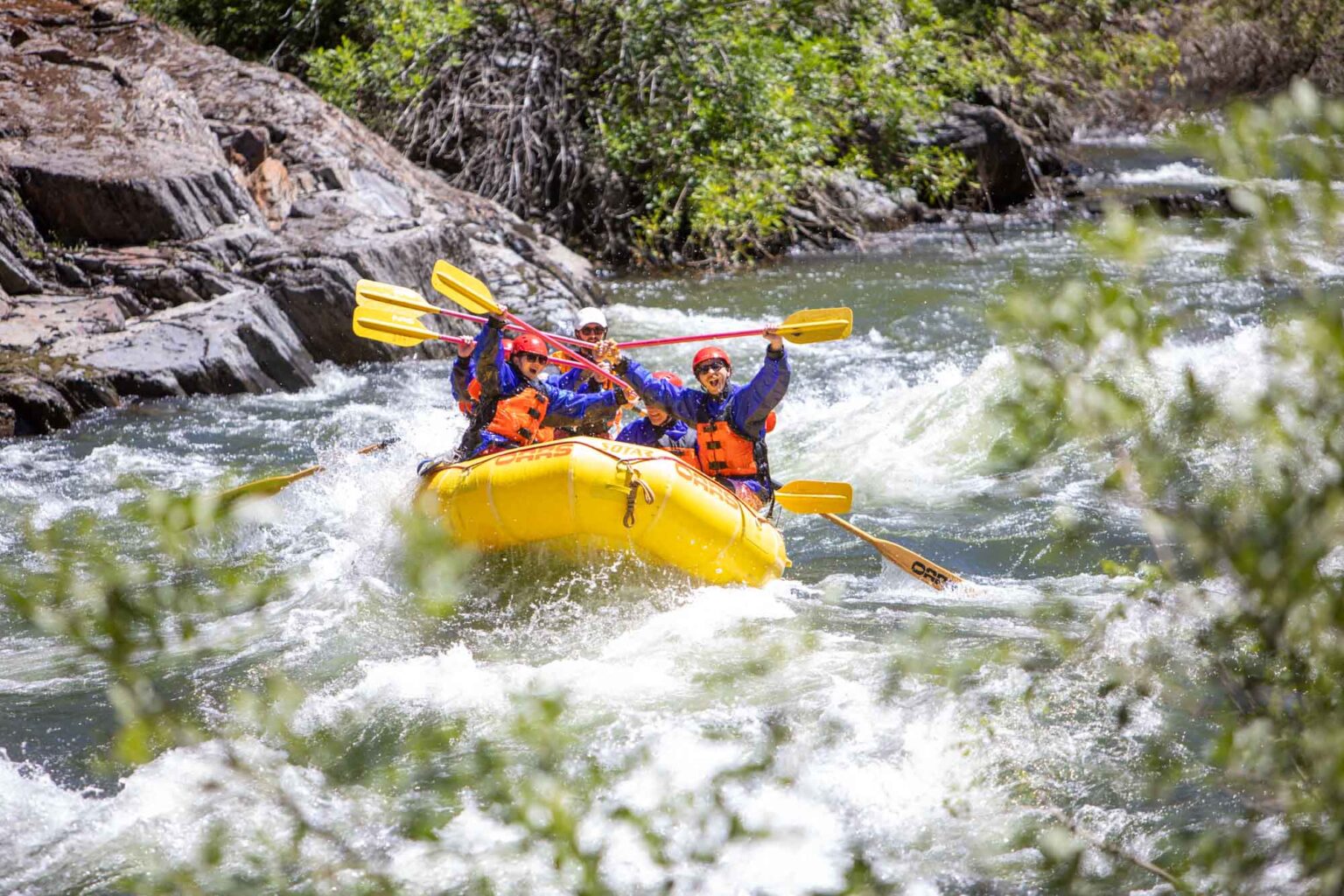 A group celebrates after rafting through a rapid on the Merced River