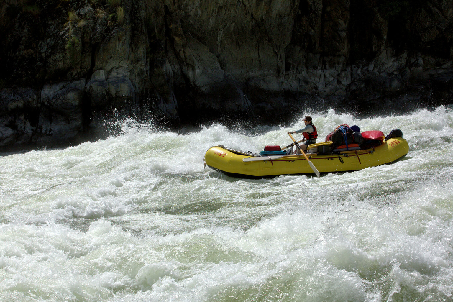 A guide rows a baggage boat through a large rapid on the Snake River.