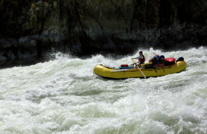 A guide rows a baggage boat through a large rapid on the Snake River.