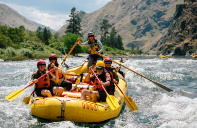 A group of people paddle through a rapid in a yellow raft on an OARS Snake River through Hells Canyon trip in Idaho.