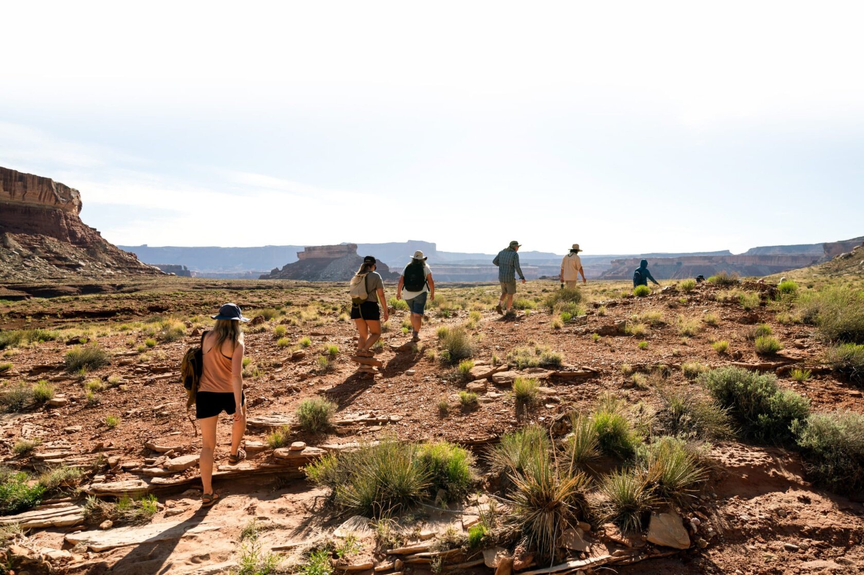 A group of people hike along a dirt path on a Stillwater and Cataract Canyon hiker trip.