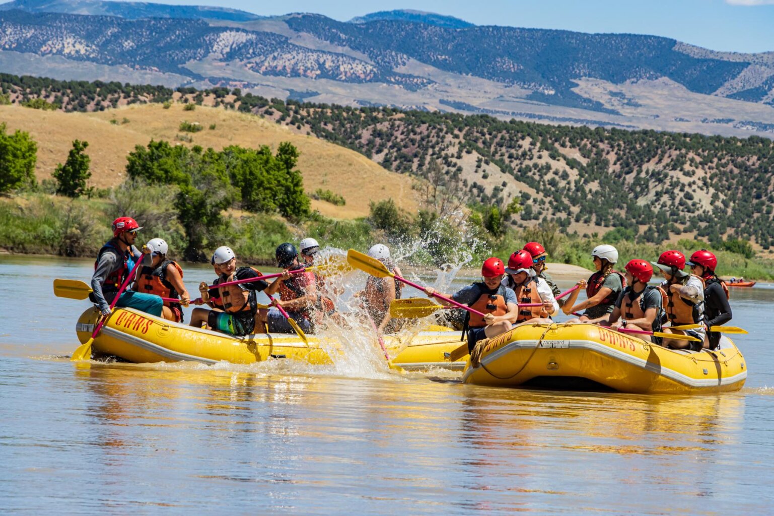 Two yellow rafts full of guests having a water fight on the Green River.