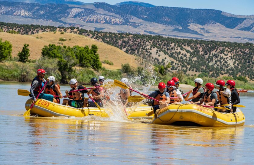 Two yellow rafts full of guests having a water fight on the Green River.