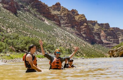 Three adult guests in personal flotation devices have a swim in the Green River through Split Mountain.