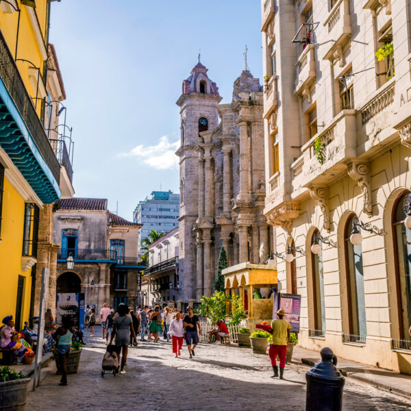 A bustling street in Cuba with vibrant and historical buildings.