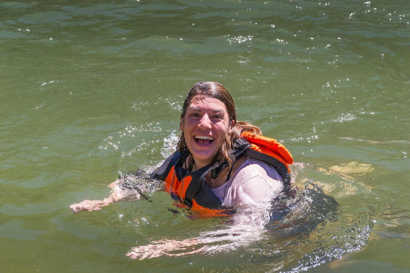 A woman smiles for the camera while swimming in the Main Salmon River in Idaho.