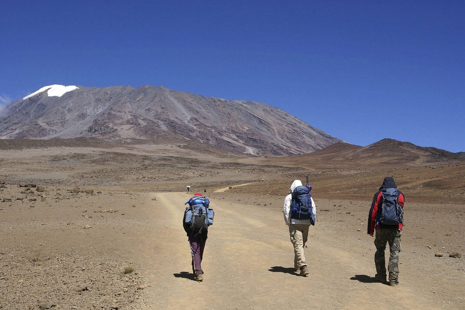 A group of hikers set out on a barren trail that leads to the summit of Mount Kilimanjaro