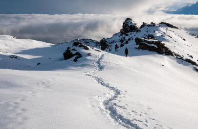 Hikers traverse a snow-covered trail that leads to the summit of Mount Kilimanjaro