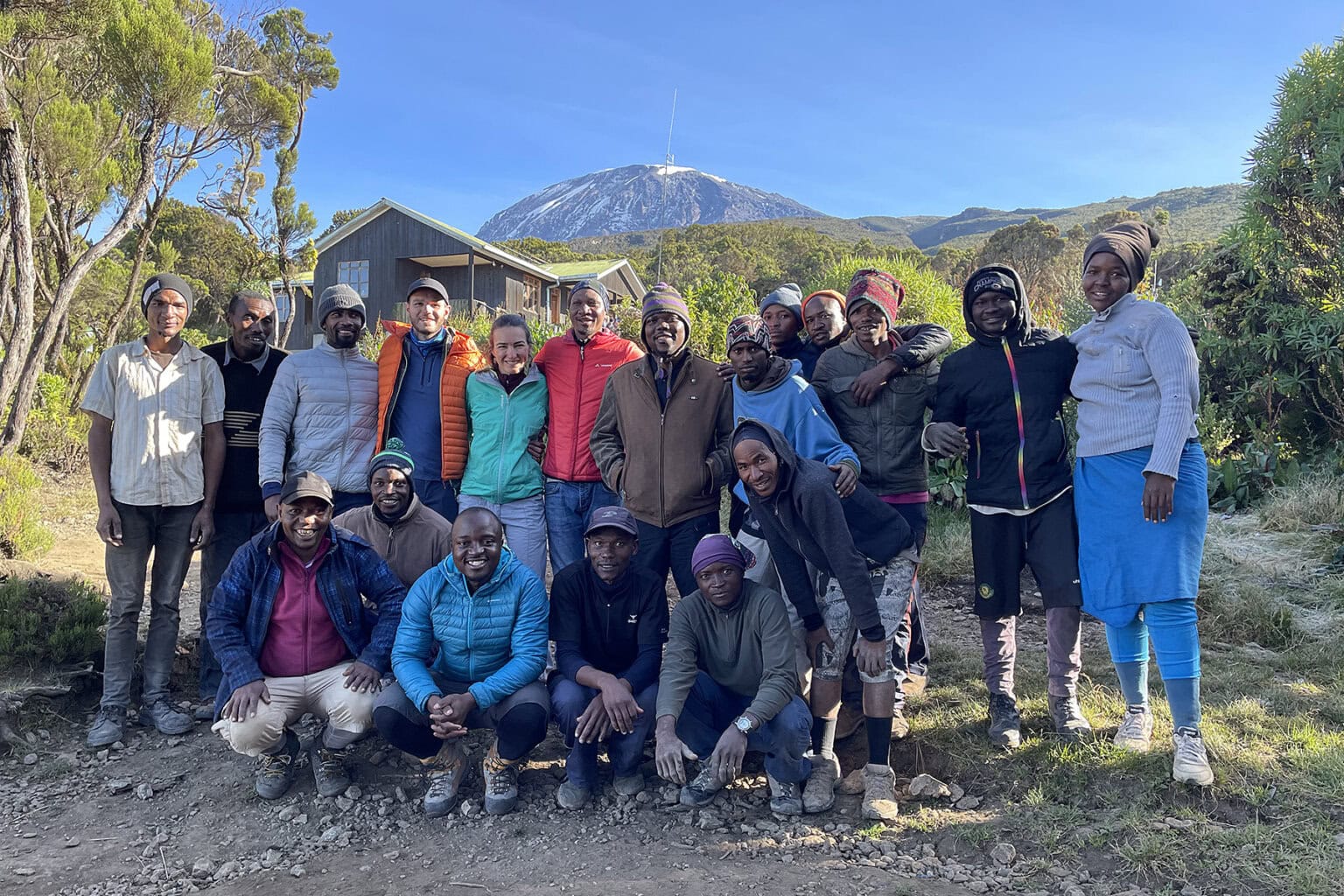 A group of hikers poses with their mountain guides and porters