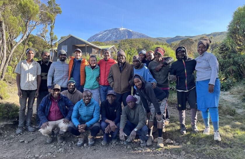 A group of hikers poses with their mountain guides and porters