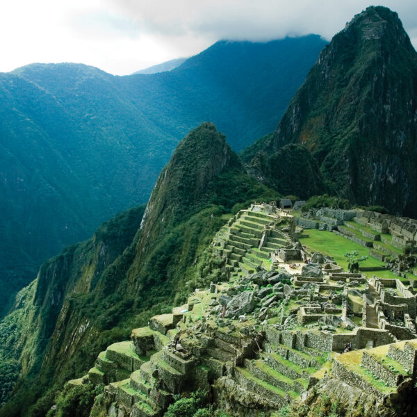 A shot of Machu Picchu surrounded by vibrant green mountains taken from above.