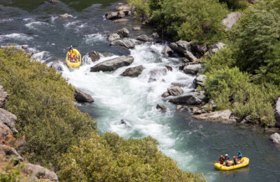 View from above of a yellow raft dropping into a big rapid while another raft downstream watches.