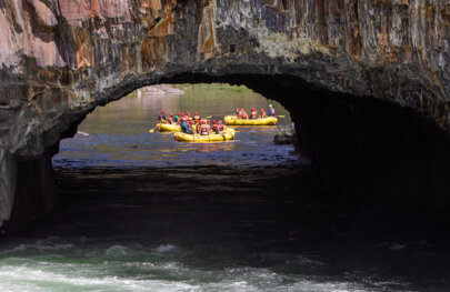 View through Tunnel Chute of three yellow rafts full of paddlers after they floated through the cave.