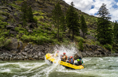 Side view of a boat full of paddlers as they crash through a wave on the Middle Fork of the Salmon River in Idaho.