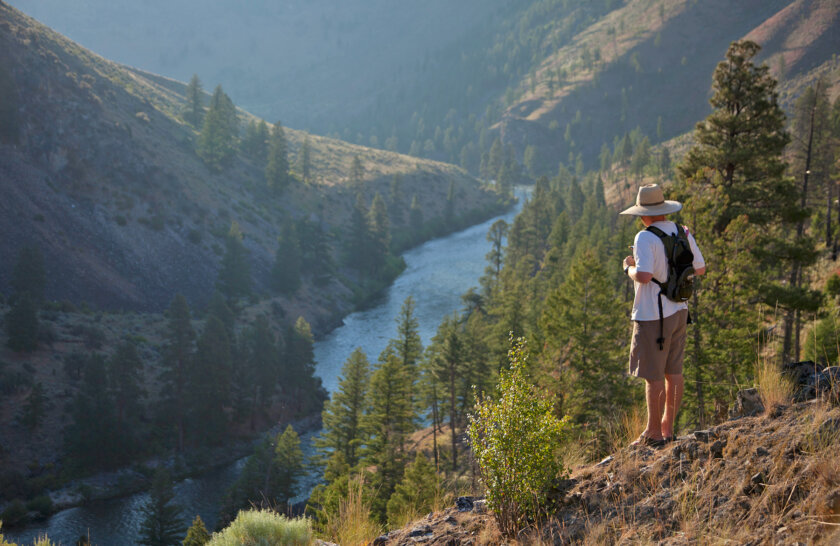 A hiker stands high above the Salmon River and takes in the view from a vista during an OARS rafting trip.