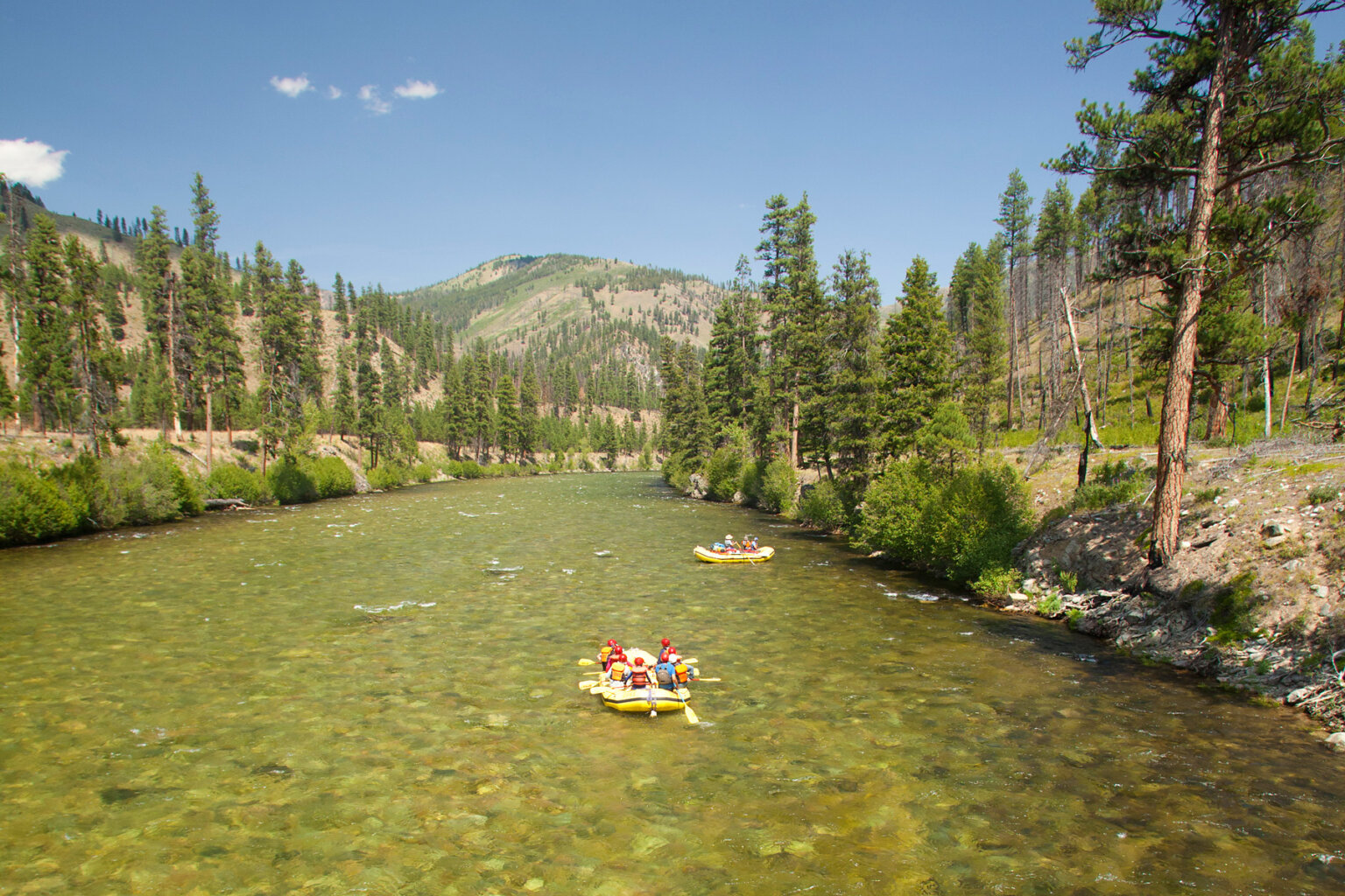 Landscape view of two yellow rafts making their way downstream on the Middle Fork of the Salmon River in Idaho.