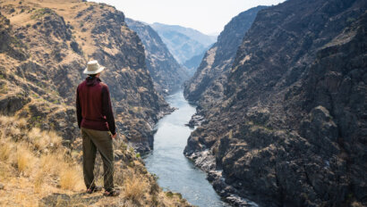 A hiker stands at a vista overlooking the Lower Salmon River and takes in the view.