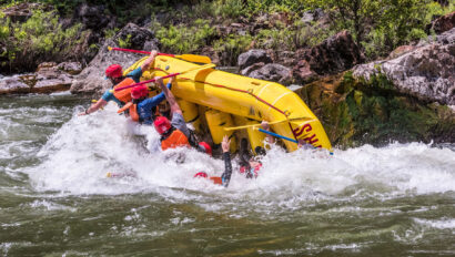 A yellow raft in mid-flip on the Tuolumne River trip in California as guests fall into the river