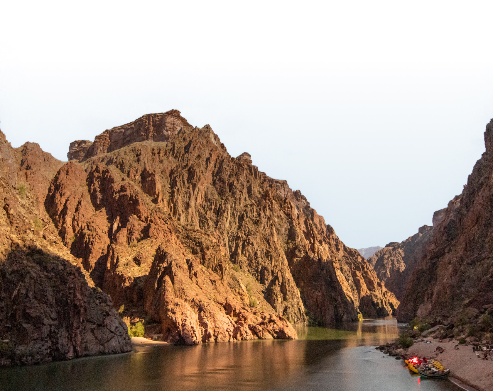 Hells Canyon rises above the Snake River and yellow rafts and dories line the shore of a sandy camp.