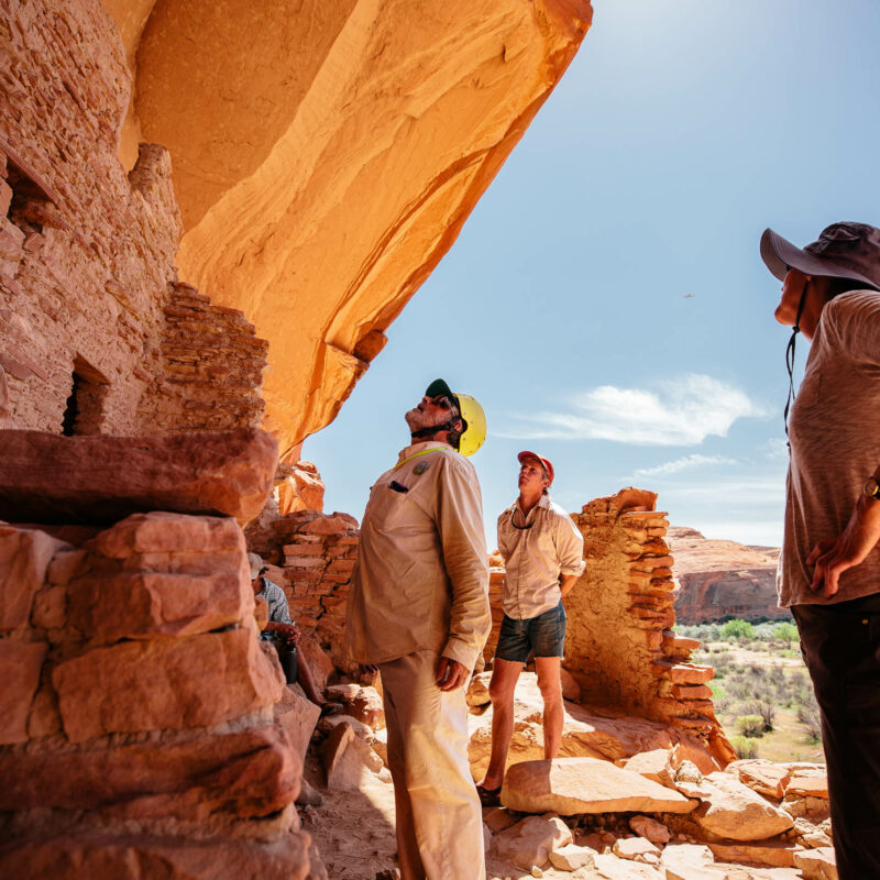 People looking up close at the archeological site near the San Juan river.
