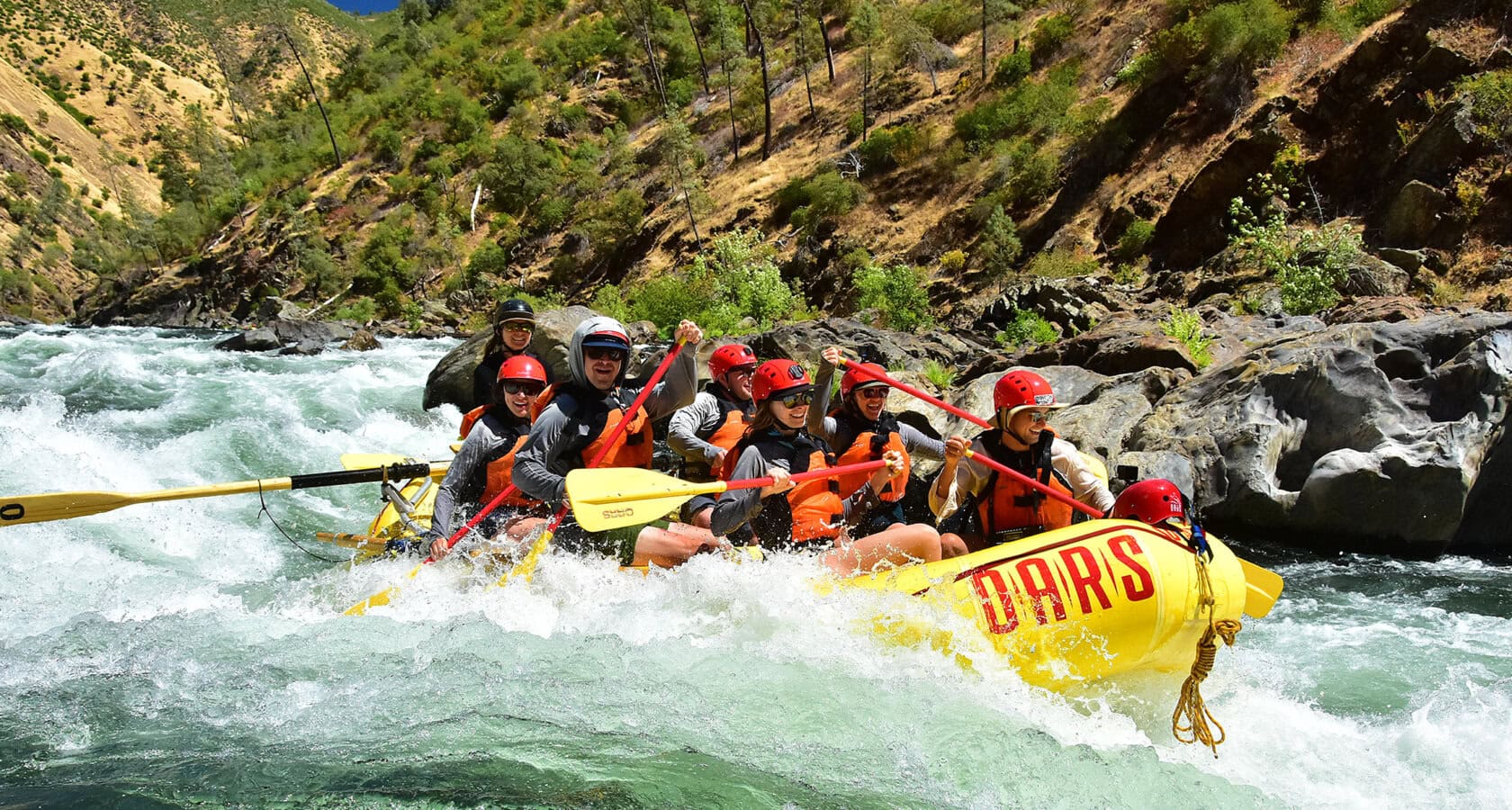 A group of adventurers rafting down California's Tuolumne River, surrounded by stunning natural scenery near Yosemite.