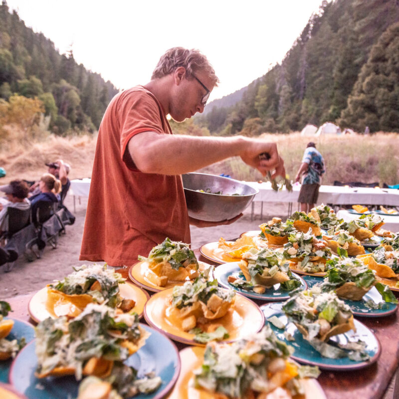 Guide preparing a gourmet meal for guests on the Rogue River.
