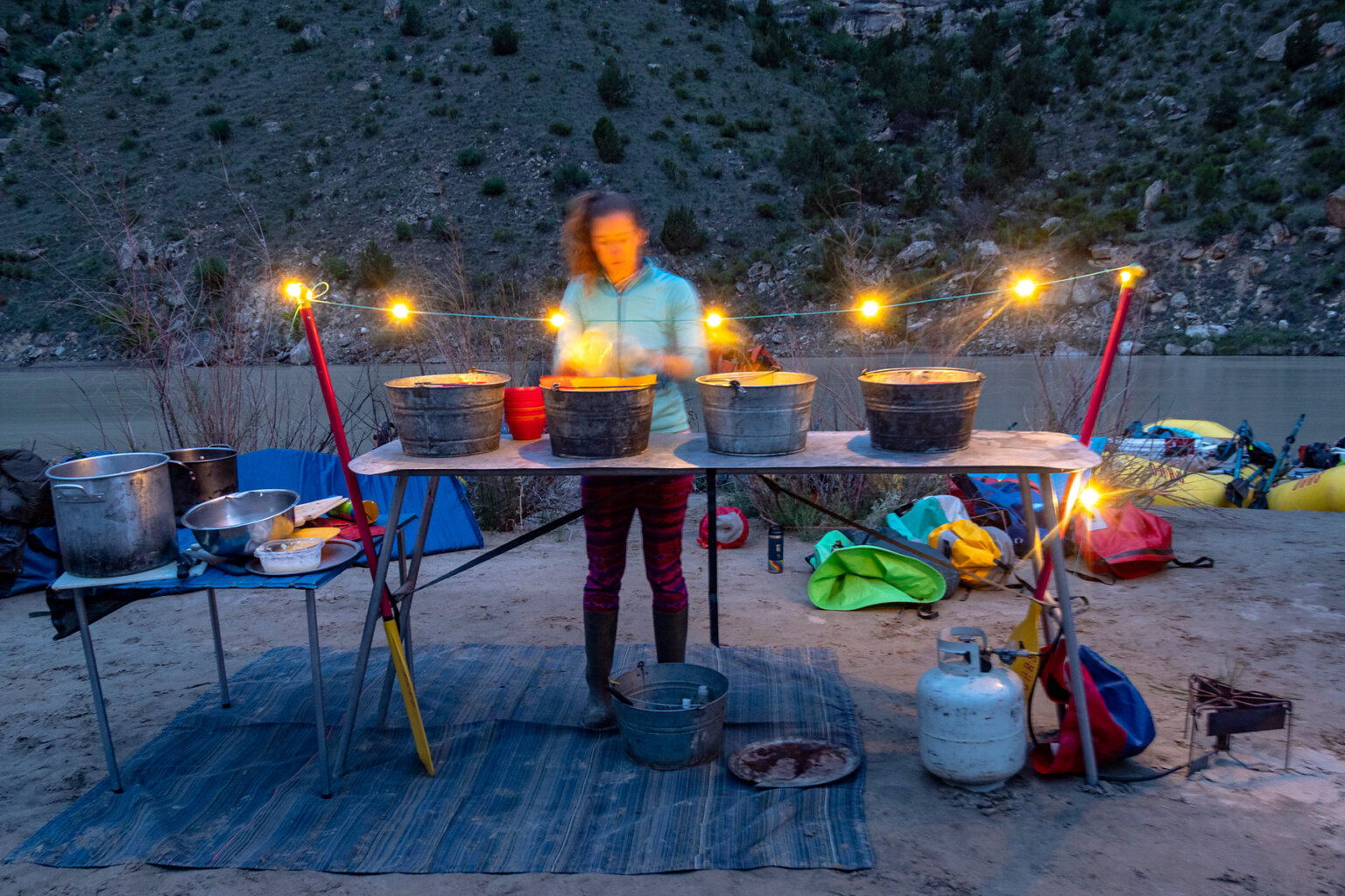 A guide washes dishes at camp after dinner is served on a Yampa River trip.