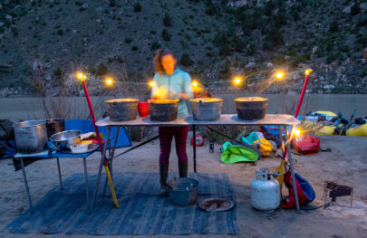 A guide washes dishes at camp after dinner is served on a Yampa River trip.