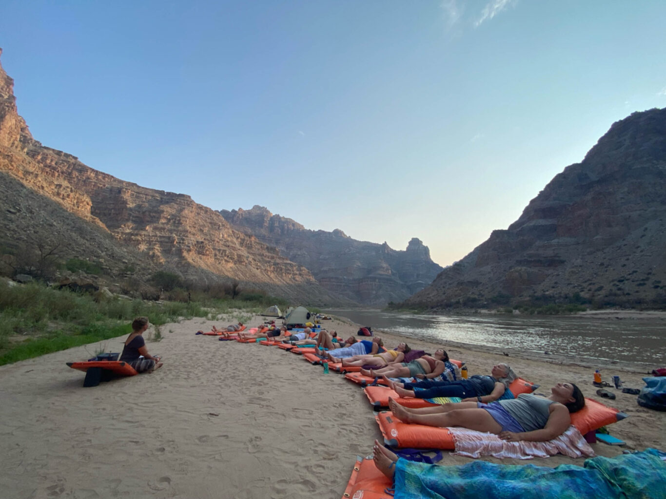 Group of travelers doing yoga on a river bank.